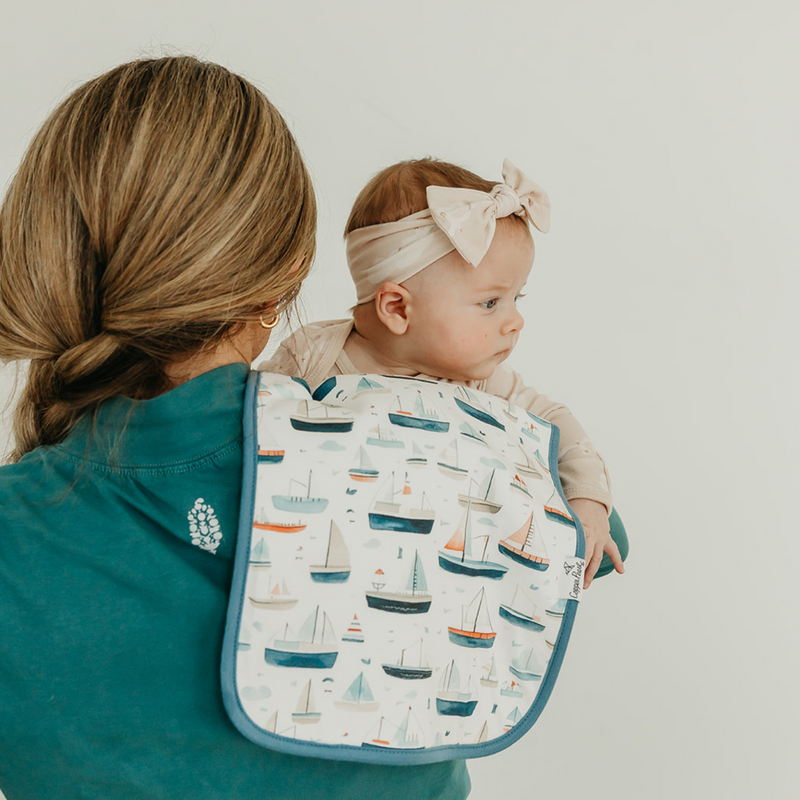 Parent holding baby with a Copper Pearl Fischer burp cloth in sailboat print over the shoulder