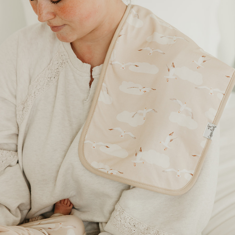 Parent holding baby with a Copper Pearl Fischer burp cloth in tan print over the shoulder