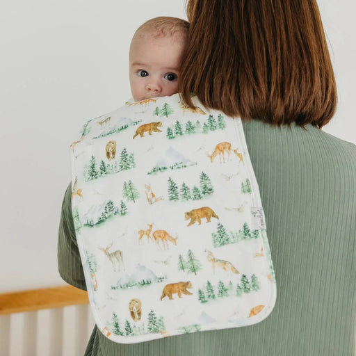 Woman holding a baby wrapped in a blanket with forest animal pattern