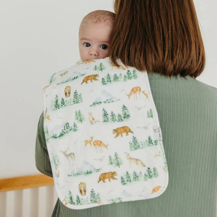 Woman holding a baby wrapped in a blanket with forest animal pattern
