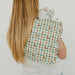 Person wearing a green and brown checkered apron on a plain background