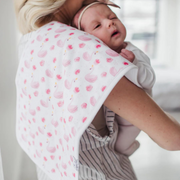 Parent holding baby with a Copper Pearl June burp cloth in pink print over the shoulder
