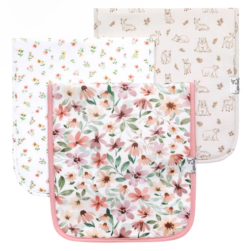 Three Natalie burp cloths laid flat in floral, ditsy floral, and woodland animal prints