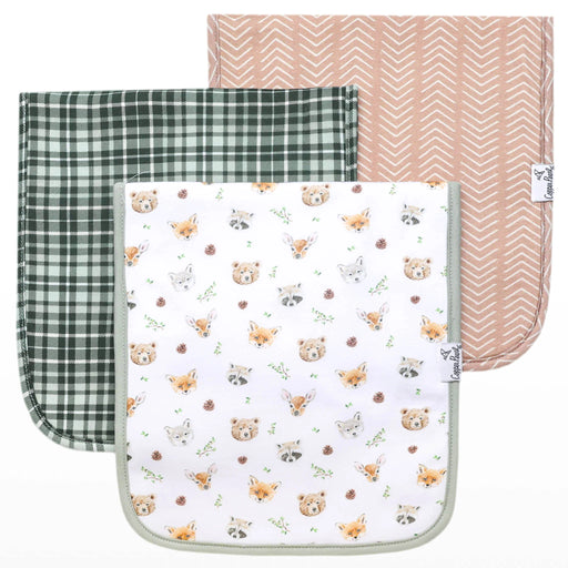 Three Wilder burp cloths laid flat in green plaid, tan herringbone, and woodland animals print