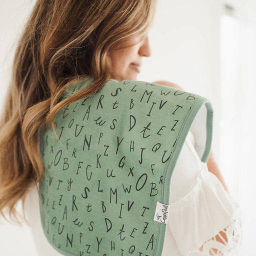 Parent holding baby with green alphabet Copper Pearl burp cloth over shoulder