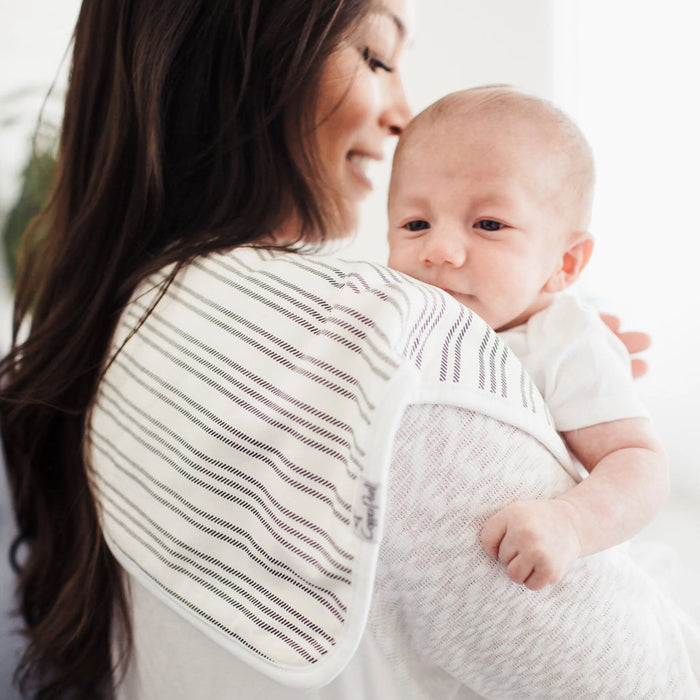Parent with striped Copper Pearl burp cloth draped over shoulder
