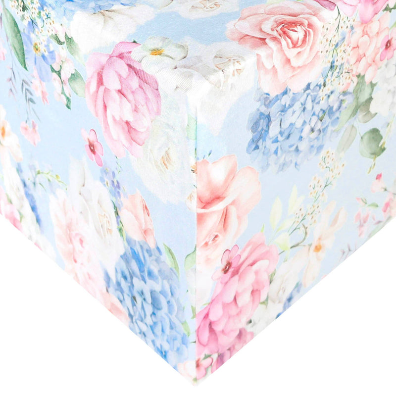 Copper Pearl premium knit fitted crib sheet in Genevieve print, pink and blue florals, shown on a mattress corner