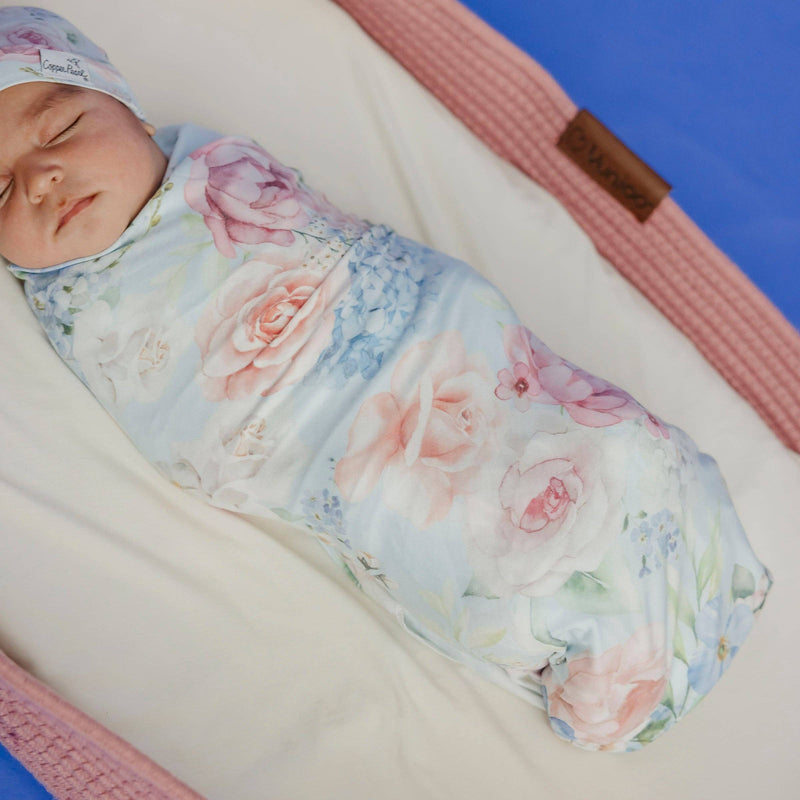 Close-up of a sleeping baby wrapped in the Copper Pearl Genevieve floral knit swaddle blanket