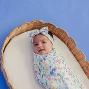 Overhead view of a baby in a basket swaddled in the Copper Pearl Josie knit swaddle blanket