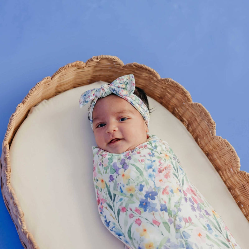 Overhead view of a baby in a basket swaddled in the Copper Pearl Josie knit swaddle blanket