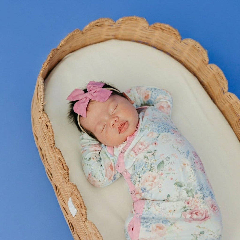 Overhead view of a newborn in a basket wearing the Copper Pearl Genevieve knotted gown