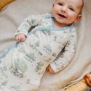 Smiling baby wearing the Copper Pearl Hundred Acre Wood newborn knotted gown, close-up of the wrap front and blue trim