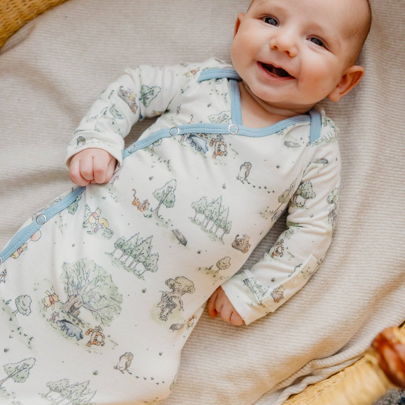 Smiling baby wearing the Copper Pearl Hundred Acre Wood newborn knotted gown, close-up of the wrap front and blue trim