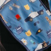 A close-up of a blue fabric item, likely a bag or pouch, printed with a playful police-themed pattern including cartoon police cars, officers, vests, badges, sunglasses, and a dog.