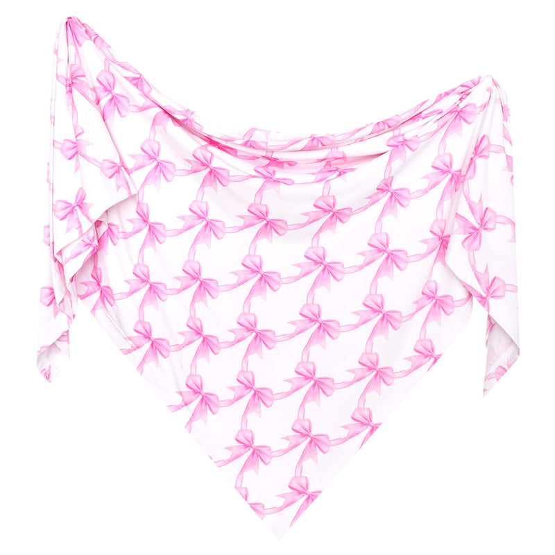A white white swaddle blanket with a repeating pink bow pattern, styled as if worn or draped like a bandana.