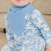 A close-up of a baby wearing a light blue bib and a white long-sleeve romper with a blue toile-style print of hot air balloons and flowers. The brand name 'Cape Fear Baby' is visible on the tag of the bib.