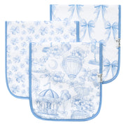 Three square baby bibs with light blue borders, displayed in a layered fan arrangement on a white background. Each bib features a delicate blue toile-style print with flowers, bows, hot air balloons, and a carousel.