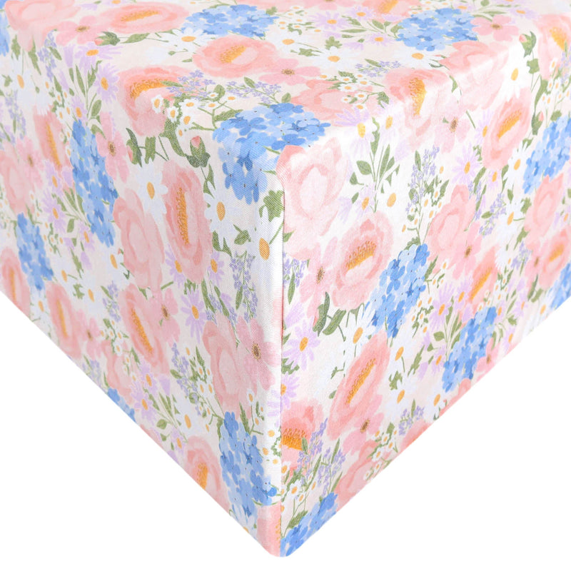 A close-up of a gift box wrapped in white wrapping paper featuring a pastel floral print with pink, blue, peach, and green flowers.
