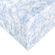 White wrapping paper with a delicate blue toile-style pattern of flowers, hot air balloons, and whimsical illustrations, shown wrapped around a gift box corner.