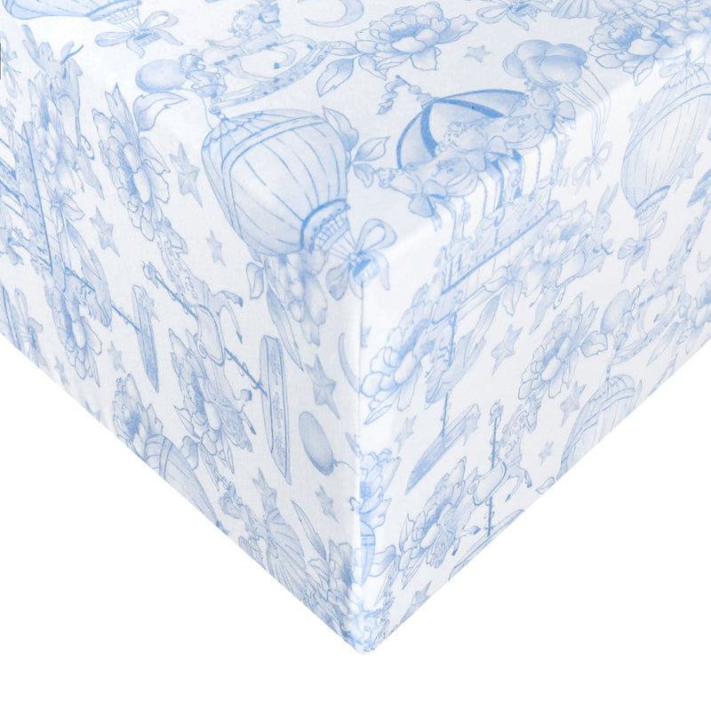 White wrapping paper with a delicate blue toile-style pattern of flowers, hot air balloons, and whimsical illustrations, shown wrapped around a gift box corner.