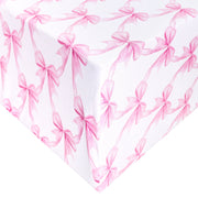 White gift wrap or fabric featuring a repeating pattern of pink ribbon bows, shown folded to display the design.