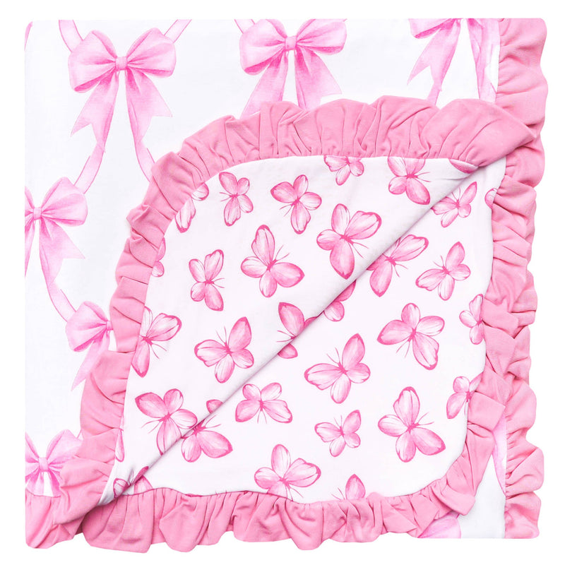 A square baby blanket or quilt with a white background, decorated with pink watercolor butterflies and bows, finished with a thick pink ruffled border.