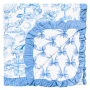 A baby bedding set featuring a white fabric with a blue toile-style print of flowers, stars, and hot air balloons, finished with a light blue ruffled border.