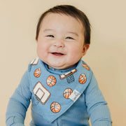Baby wearing a blue sweater with basketball patterns on a beige background
