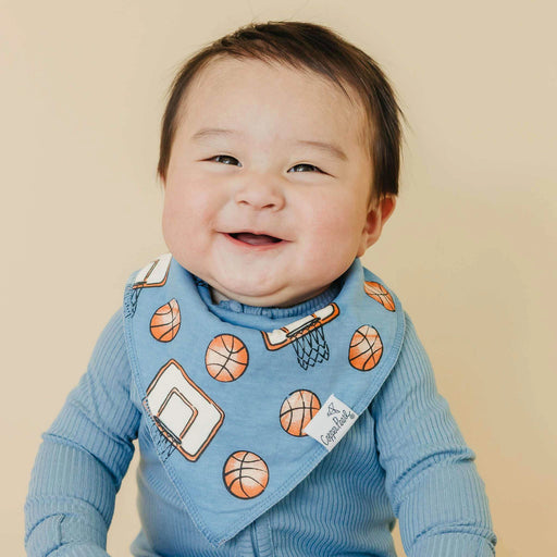 Baby wearing a blue sweater with basketball patterns on a beige background