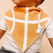 Child wearing an orange bib with white crosshatch pattern and a visible brand tag on a beige background