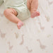 Baby lying on Charlie Farmhouse Goose crib sheet with goose pattern visible