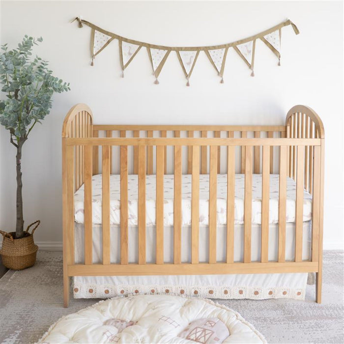 Nursery room with wooden crib dressed in Charlie Farmhouse Goose crib sheet