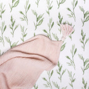 Pink fabric with tassel on a white background with green leaf pattern