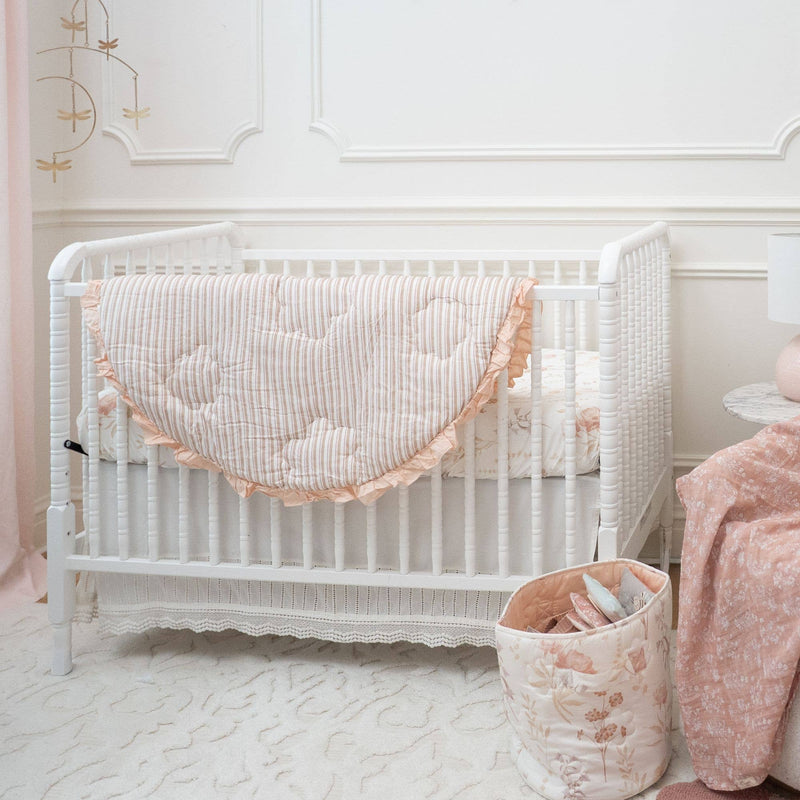 White crib with pink bedding in a nursery setting