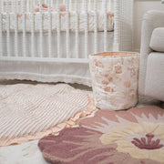 Nursery with crib, floral-patterned rug, and decorative basket.