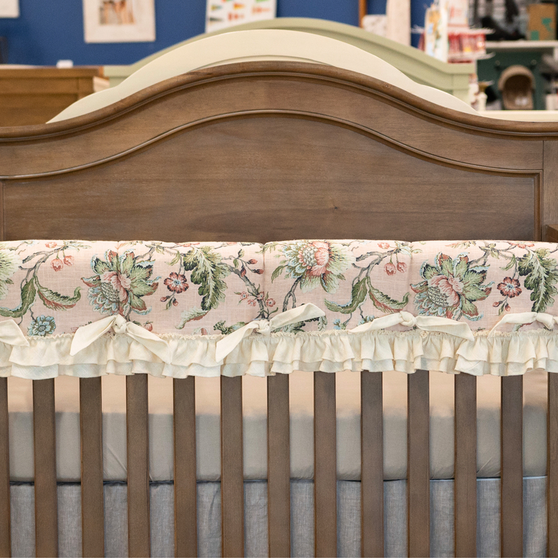 Wooden crib with floral-patterned crib skirt in a nursery setting