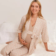 Woman in a floral robe sitting on a white bed