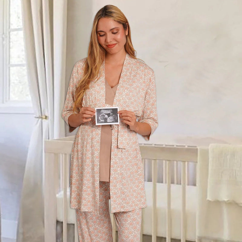 Woman holding a ultrasound photo in a nursery with a crib and white curtains.