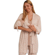 Woman wearing a beige patterned pajama set holding a baby on a white background