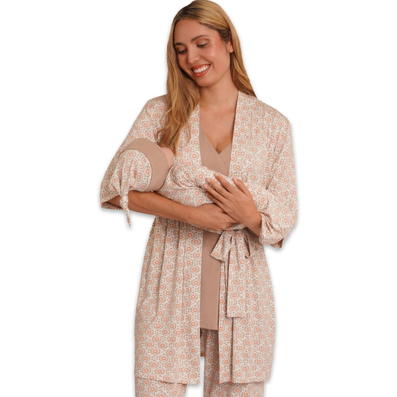 Woman wearing a beige patterned pajama set holding a baby on a white background