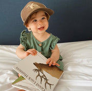 Smiling baby in a hat reading the Good Luck Hunters board book