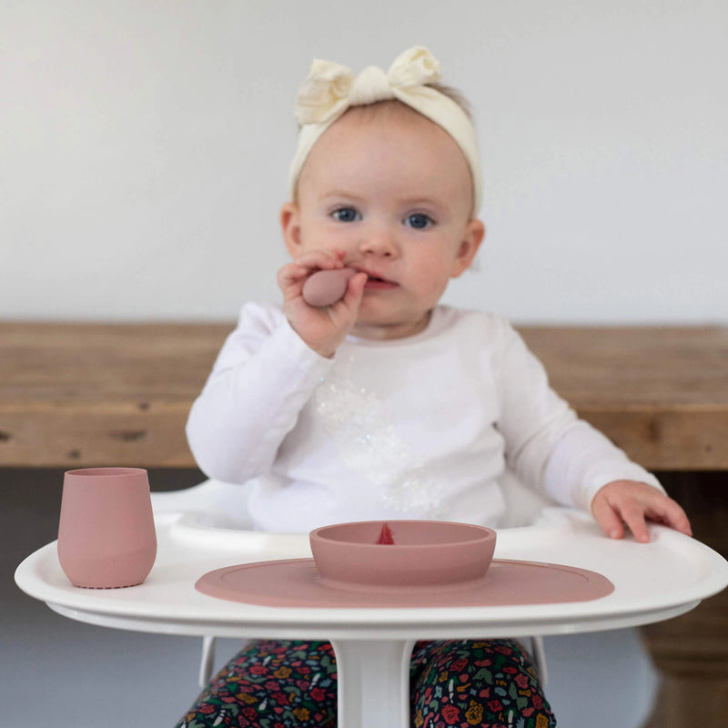 Baby self-feeding with a Blush ezpz Tiny Spoon at a high chair