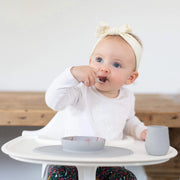 Baby eating with a Gray ezpz Tiny Spoon with matching ezpz bowl and cup