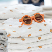 Orange sunglasses on a stack of folded fabric with a blurred background