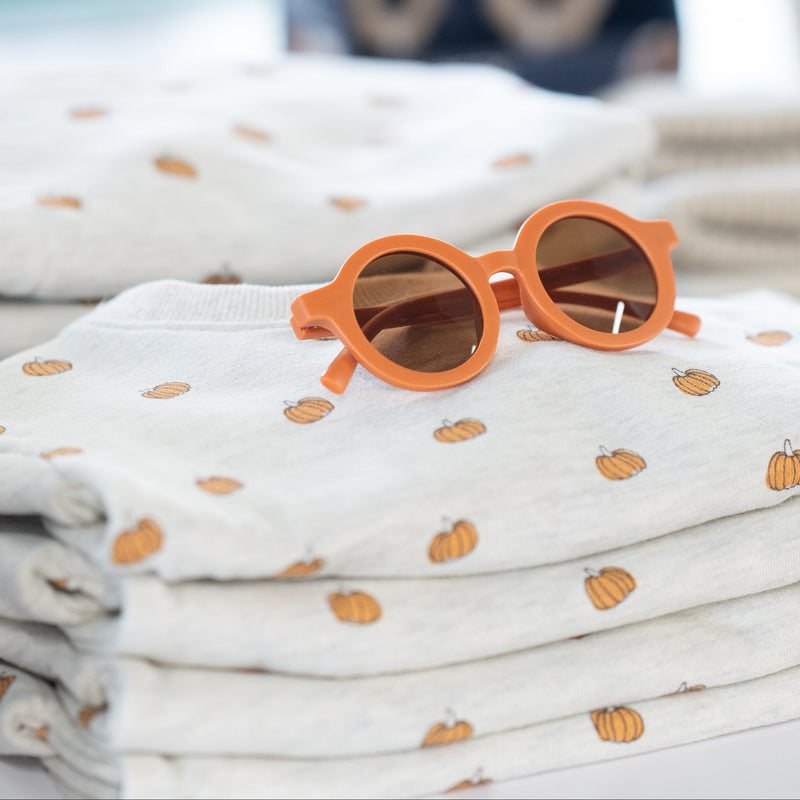 Orange sunglasses on a stack of folded fabric with a blurred background