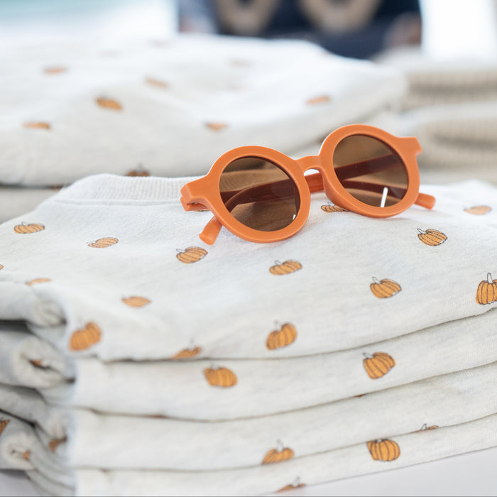 Orange sunglasses on a stack of folded fabric with a blurred background