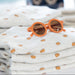 Orange sunglasses on a stack of folded fabric with a blurred background
