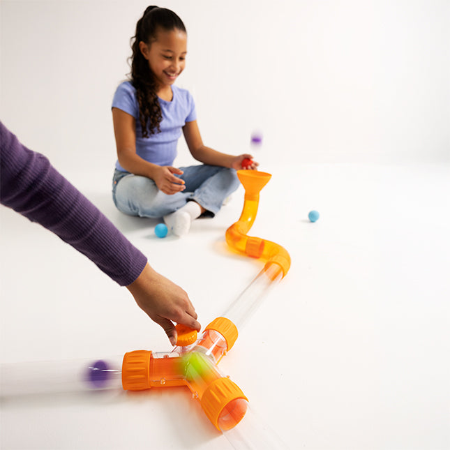 Child playing with a colorful marble run toy on a white background