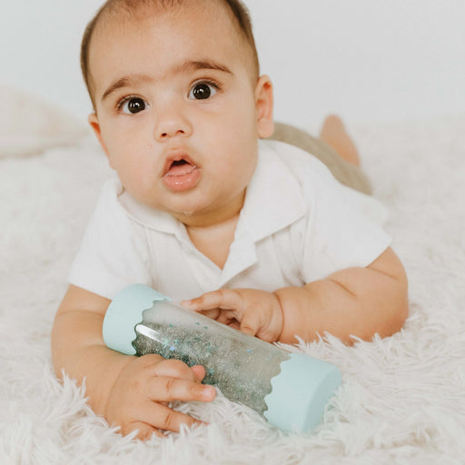 baby on tummy rolling soft mint calm down bottle during playtime