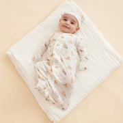 Newborn wearing magnetic gown while lying on blanket